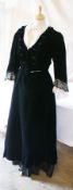 A Victorian black velvet walking dress with a lace fichu, the sleeves trimmed with black and cream
