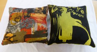 Two large cushions, modern abstract designs, one black and yellow the other reds, oranges and