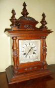 Late Victorian walnut mantel clock, having carved domed top, three turned finials, turned split