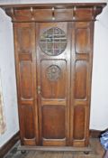Arts and Crafts style oak wardrobe, the door with circular leaded glass panel and carved panel,