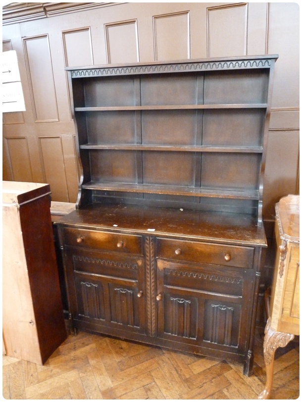 A reproduction stained oak dresser with three open shelf rack, two frieze drawers with carved
