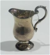 A George V silver cream jug, of plain form, with scroll handle, raised on a circular foot,