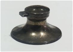 George V silver capstan-shaped inkwell with hinged cover, on raised spreading circular base,