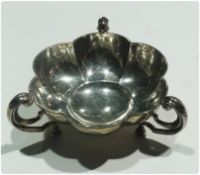 A George V silver circular bon-bon dish of lobed form, with triple scroll handles to bun feet, by