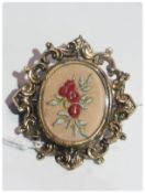 Victorian gold coloured metal brooch with embroidered flowers to centre with scroll border