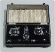 A silver three-piece cruet set, comprising:- salt and mustard pots with blue glass liners, and a