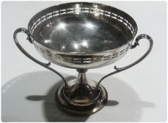 An Edwardian silver two-handled pedestal prize trophy, with fretwork pierced border, twin scroll