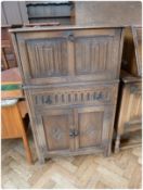 A reproduction oak drinks cabinet, the upper section with mirrored shelf and rising top, frieze