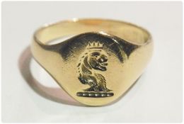 Gold coloured metal signet ring engraved with crowned lions head to crest