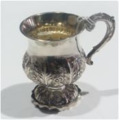 A Georgian silver cup, with foliate scroll handle and floral repousse decoration to circular foot,
