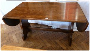 A modern oak drop flap refectory dining table, with trestle supports, united by central stretcher,