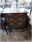 A reproduction oak side cupboard, of linenfold doors above a frieze drawer, on baluster turned