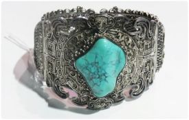 Eastern silver coloured metal and turquoise bangle style bracelet, the misshapen large turquoise set