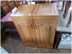 A modern hardwood drinks cabinet, the top with opening hinged front, fitted cupboards below