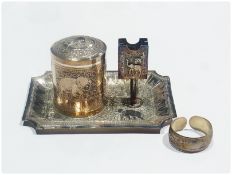 An Indian silver circular cigarette box and cover, on stand, with matchbox holder, together with a