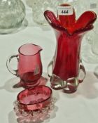 Small cranberry glass jug, a cranberry glass bowl with frilled white glass edges, and a red art