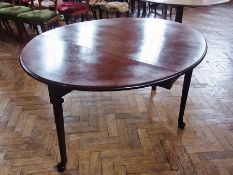 A Georgian red walnut oval top dining table, the moulded edged plain frieze, raised on turned
