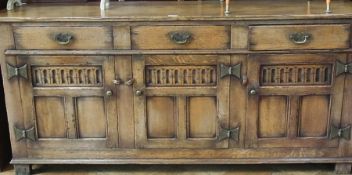 A reproduction oak Jacobean style dresser with three frieze drawers and three panelled and fluted