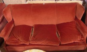 An old three-seater winged sofa, russet coloured dralon upholstery and loose cushion seats, on