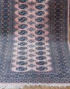 Persian style wool rug, pink ground decorated with two rows of quartered elephants foot guls, 96 x