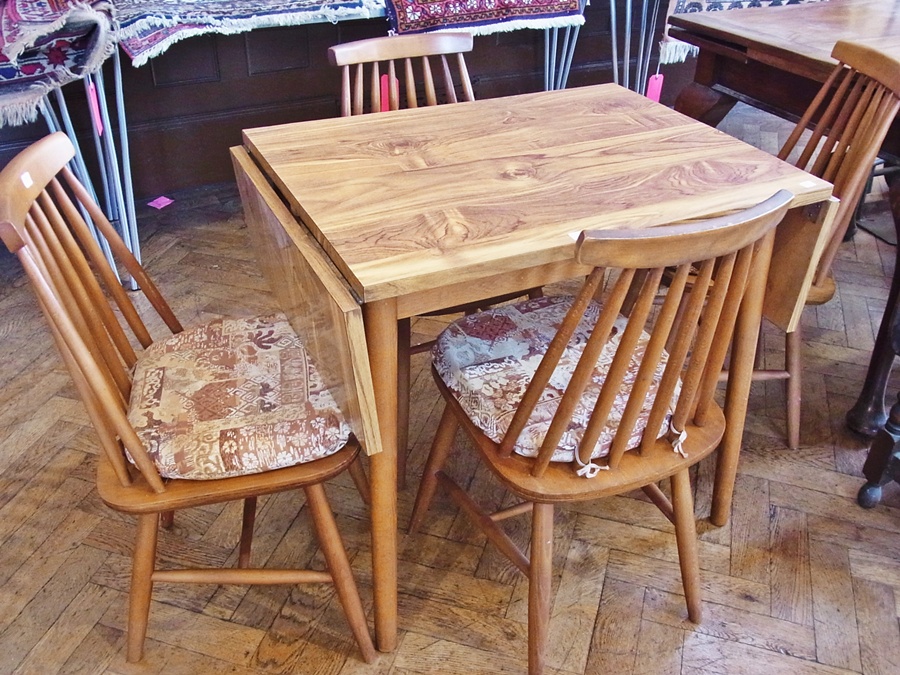 A walnut effect dropleaf dining table, on turned tapering legs, together with a set of four