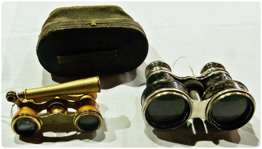 A pair of opera glasses in a leather case, together with another pair with handle