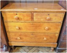 A modern stained pine chest of two short and two long drawers with wooden handles, raised on