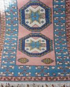 Turkish wool rug, pink ground with two geometric medallions in shades of blue and pink, 78 x 130cm