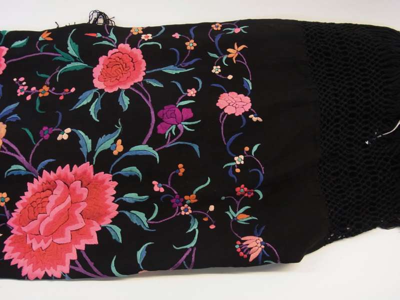 A large shawl, embroidered bright flowers on a black ground with a deep crocheted fringe