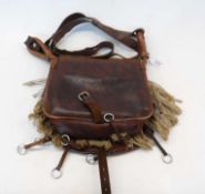 A leather and fur hunting bag with various attachments and long strap