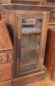 A beech glazed storage cupboard, the panelled door enclosing three shelves raised on a plinth