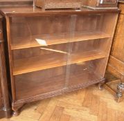 Modern mahogany bookcase, the glass sliding doors enclosing three shelves on short cabriole legs,