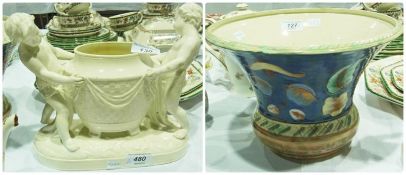 Creamware centrepiece, having two cupids holding a basketweave vase, standing on a raised plinth