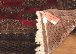 A Tekke design wool rug, with deep red field and overall floral gul decoration, within multiple