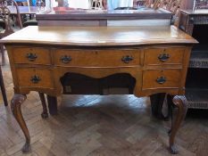 A reproduction walnut serpentine-front writing table, with inset writing surface, frieze drawer with