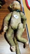 Early twentieth century plush monkey, having glass eyes, felt face and jointed limbs, wearing