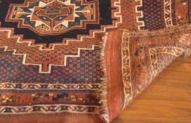 A Shirvan style wool rug, with three central medallions in a dark blue field, within multiple floral