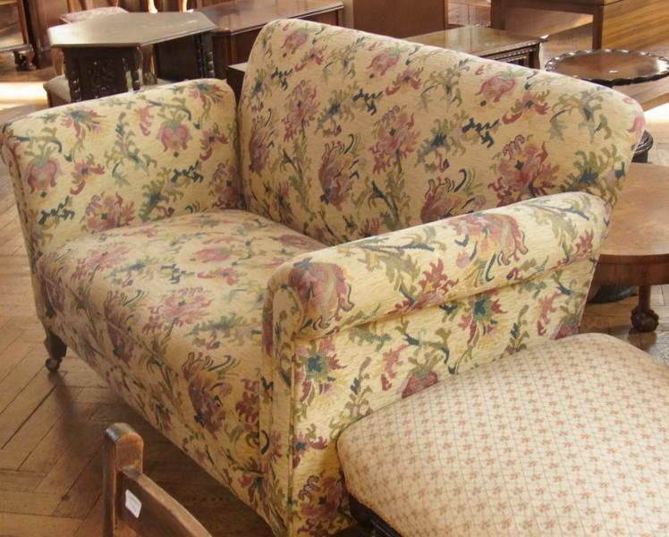 Two-seater drop-end sofa, upholstered with floral sprays on a cream ground, on shaped feet and
