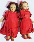 A pair of small early twentieth century dolls wearing red dresses (2)