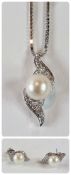 18ct gold pearl and diamond pendant, the central pearl flanked two diamond set scrolls on fine box