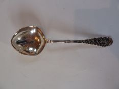 A continental silver sifter spoon with pierced bowl, the handle with scrollwork decoration