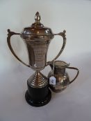 A silverplated hot water jug with cane handle and a presentation trophy cup from James Peiris and Co