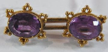 Gold-coloured metal and amethyst bar brooch, set two oval faceted amethysts, having ball cluster