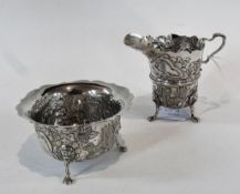 A Georgian style silver cream jug, with cut-card borders, foliate repousse decoration with scroll