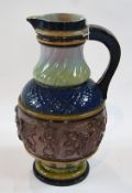 A large continental style stoneware jug, various decorations and colours on a round pedestal foot,