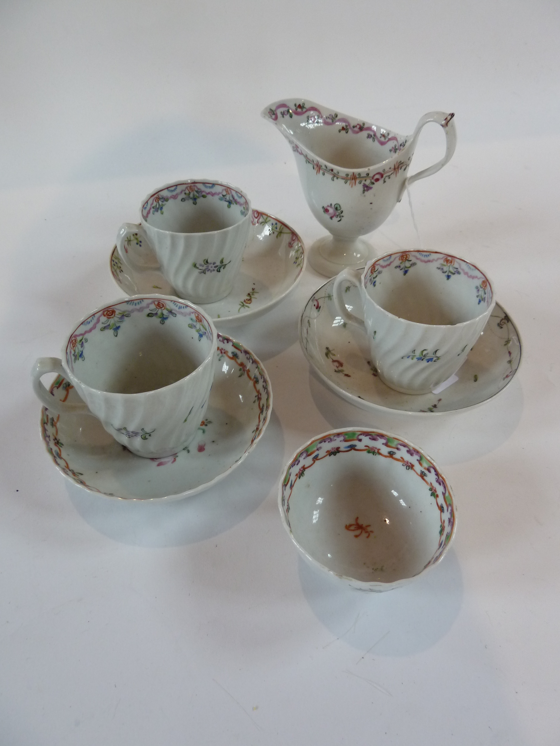 A Newhall style pedestal cream jug together with three cups and saucers and a tea bowl