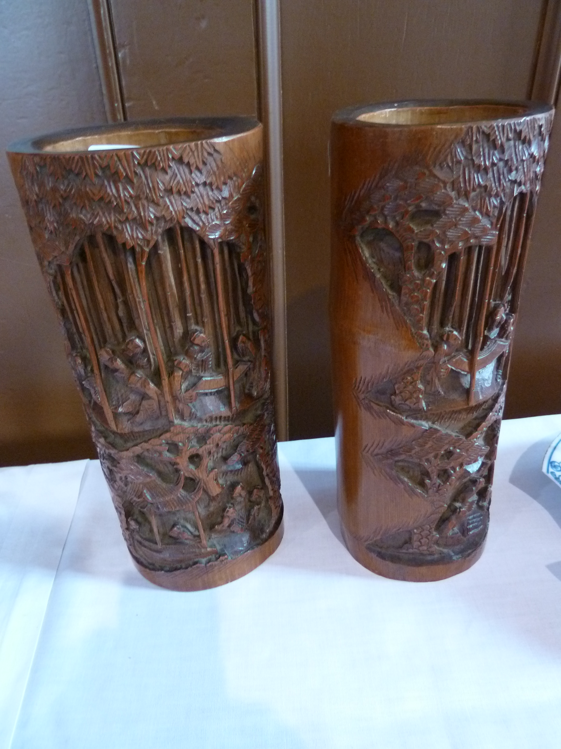 Pair Japanese carved bamboo vases, each decorated with figures and buildings in woodland, 28cm high