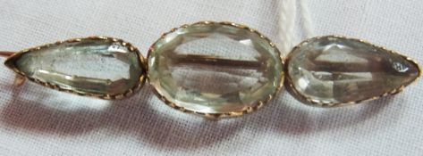 Gold coloured metal and aquamarine coloured stone set brooch, having oval cut central stone, flanked
