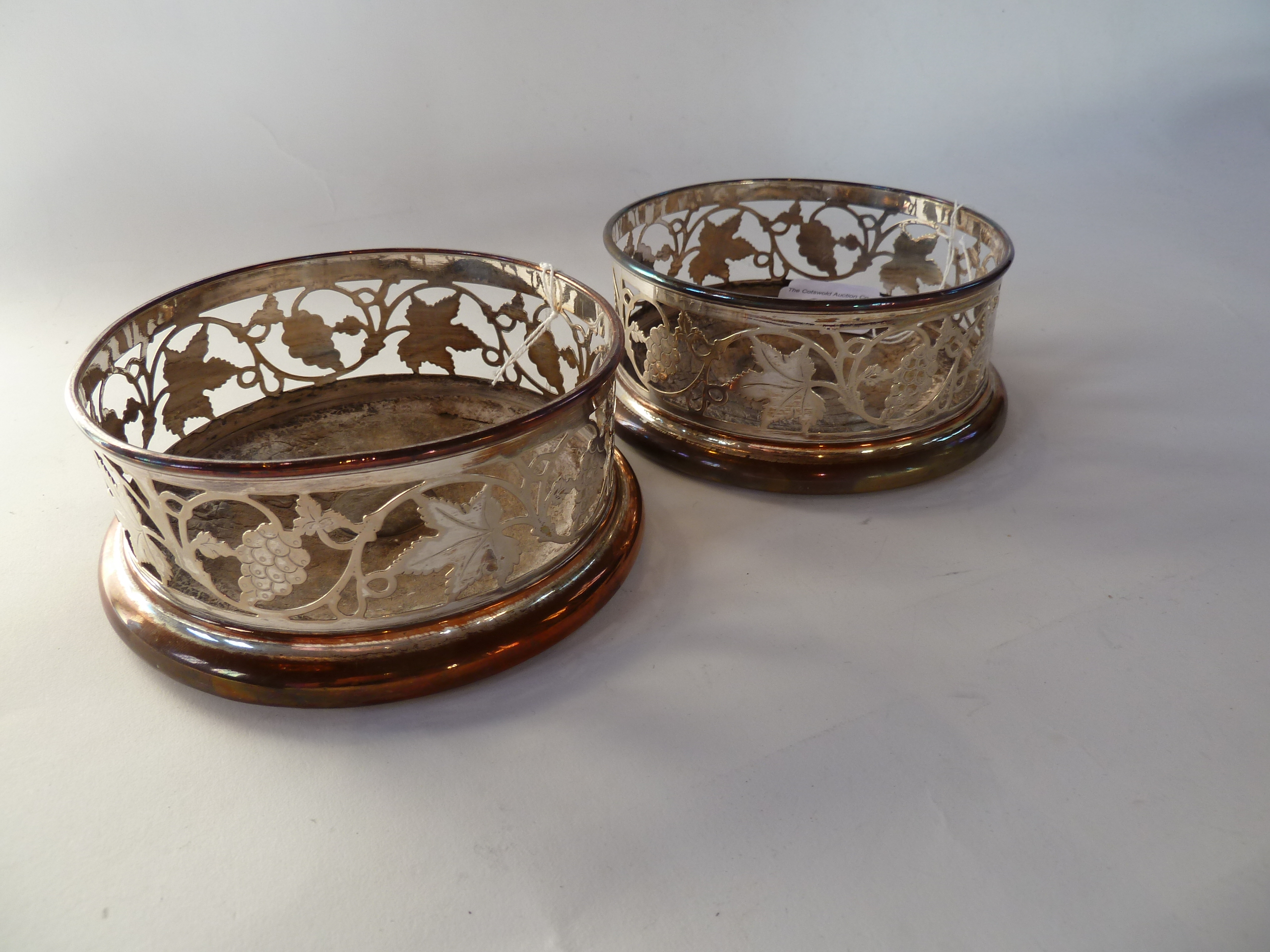 A pair silverplated coasters, with openwork vine and leaf design, wooden bases