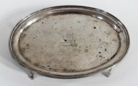 Edward VII silver oval card tray, with raised border, engraved crest, raised on four scroll feet,